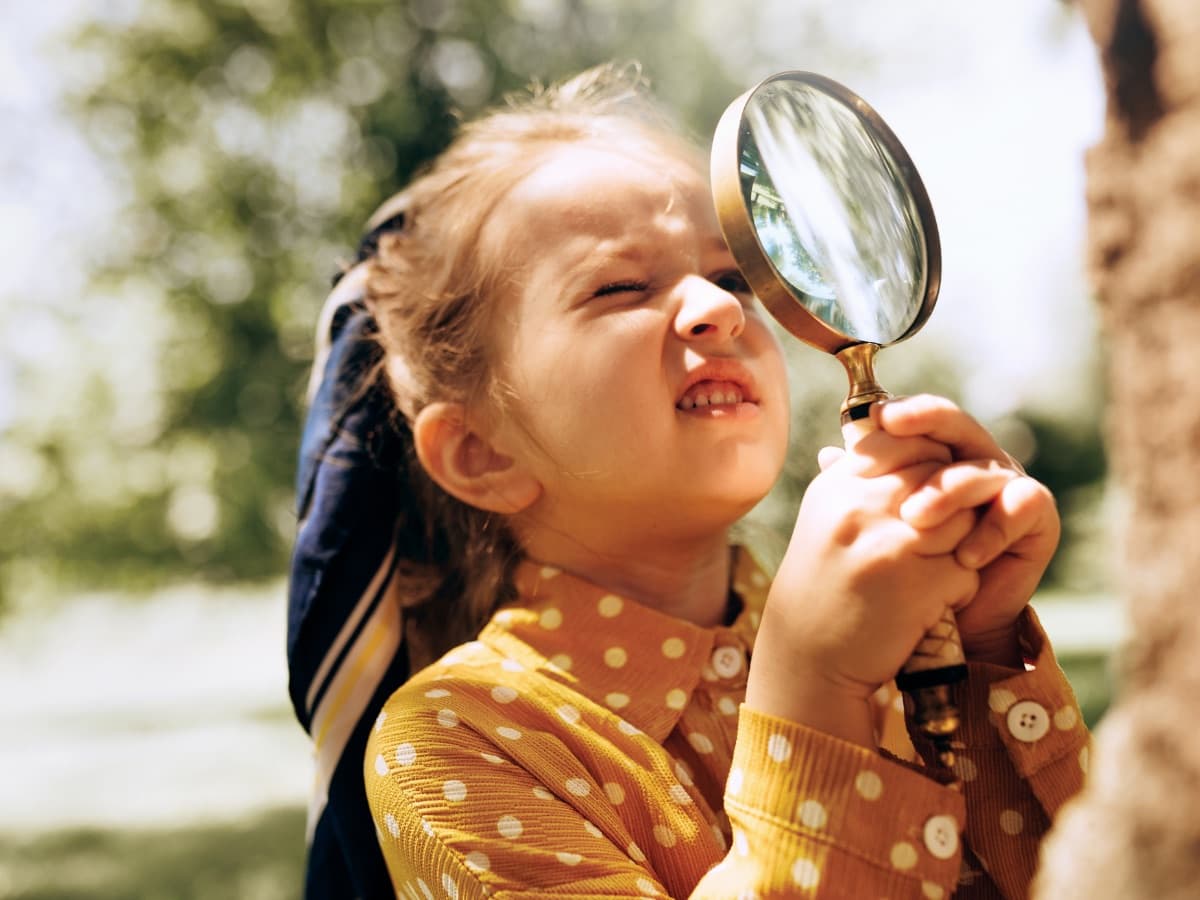 A child exploring outdoors with a magnifying glass