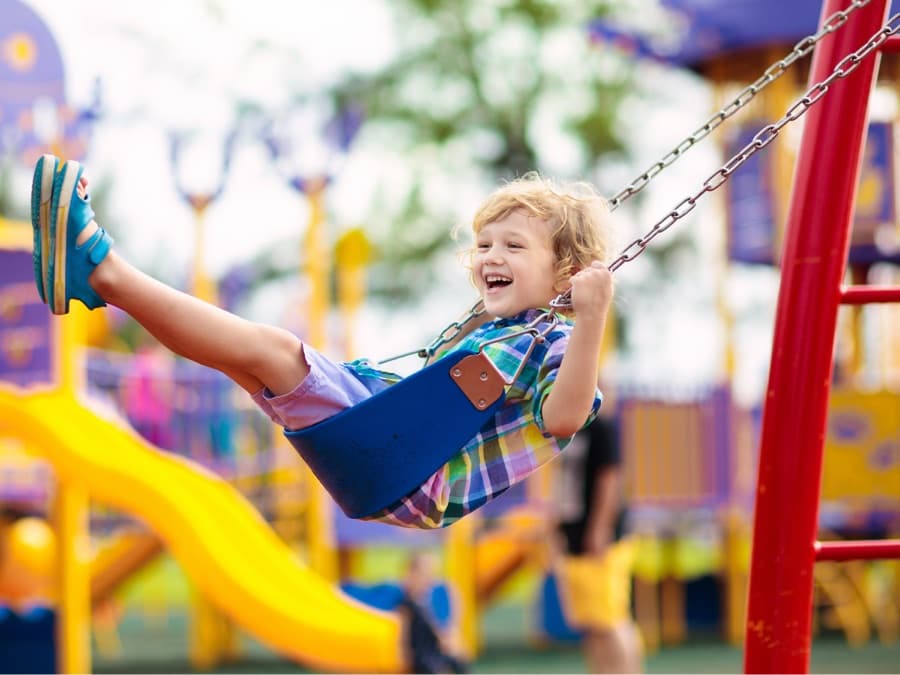 A child laughing on a playground swing