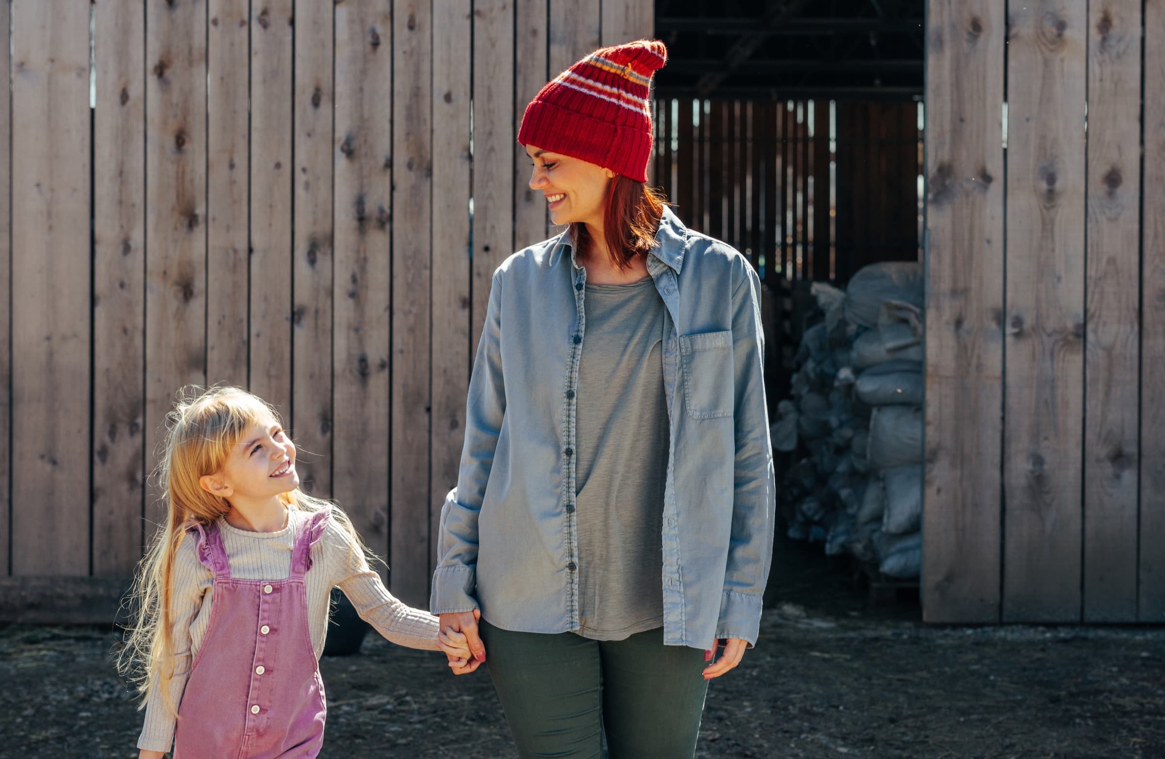 A mum and daughter holding hands on a farm day out